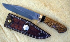 A photo of a camp knife with fancy leather sheath